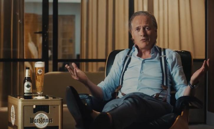 Jort Kelder zit naast het gouden Warsteiner krat waar een flesje en glas bier bovenop staat